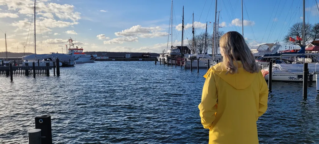 Lea Jansen im gelben Mantel vor Segelbooten im Hafen